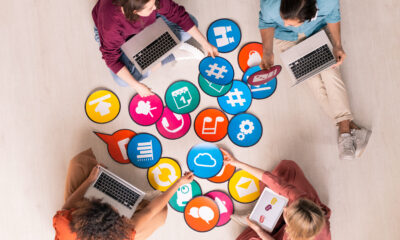 Aerial view of people with laptops surrounded by colorful app and technology icons