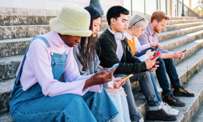 Group of young people sitting on outdoor steps looking at their phones
