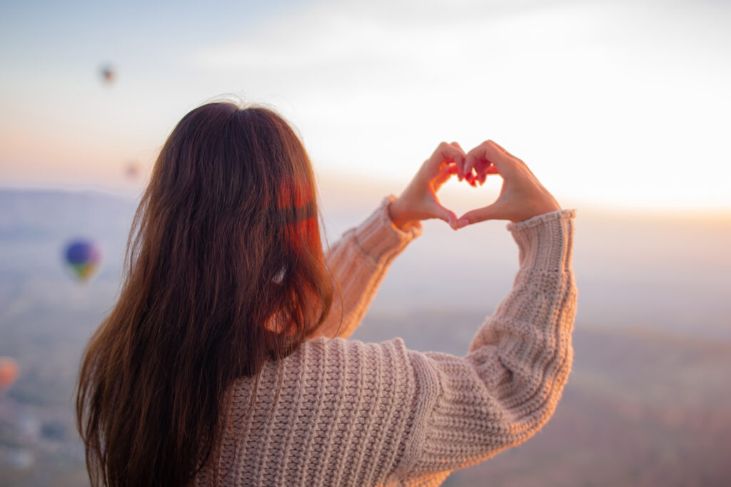 A woman makes a heart shape with her hands