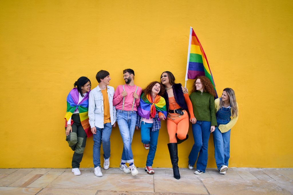 A group of young people representing the LGBTQ+ community smile